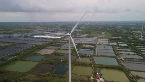 Wind-Power-Turbine-Aerial,-Windmill-generating-clean-renewable-energy-in-green-agricultural-field-aerial-landscape