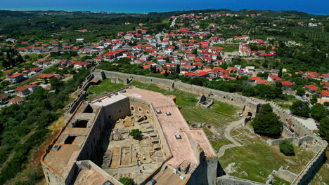 Chlemoutsi-Castle-Museum---aerial-view-overlooking-the-castle-courtyard,-picturesque-village,-and-Iberian-Sea---aerial-reveal