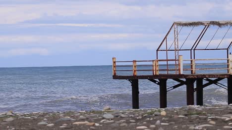 Pier-on-the-shore-of-the-Black-Sea-in-Batumi,-Georgia,-with-sea-waves-crashing-at-the-coastal-area,-highlighting-the-concept-of-maritime-beauty-and-coastal-landscapes