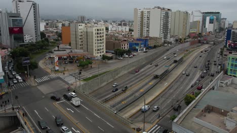 Drone-Shot-of-Busy-Traffic-in-Downtown-Neighborhood-of-Lima,-Peru,-Avenues,-Bridge-and-Buildings