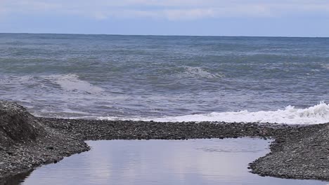 Sea-waves-crashing-on-the-coastal-shores-with-a-vast-horizon-in-the-backdrop,-located-in-Batumi,-Georgia,-highlighting-the-concept-of-natural-beauty-and-coastal-landscapes