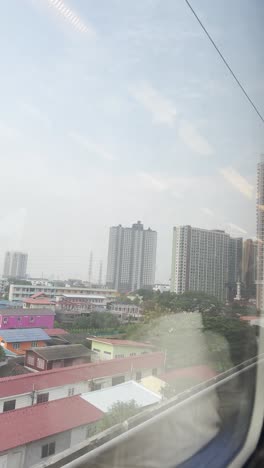 local-metro-train-window-seat-exploring-Bangkok-city-like-buildings,-houses-local-street-markets