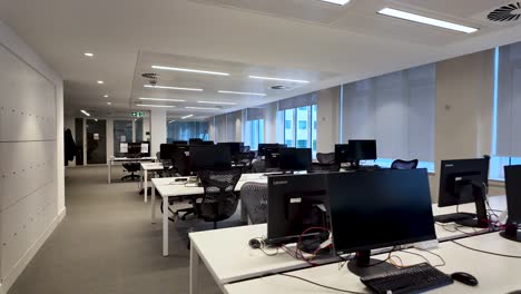 Modern-open-space-office-with-rows-of-computers-on-desks-lit-by-daylight-entering-by-the-windows