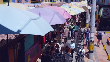 Los-Turistas-Pasean-A-La-Sombra-Bajo-Las-Sombrillas-De-La-Calle-En-Guatapé,-Colombia