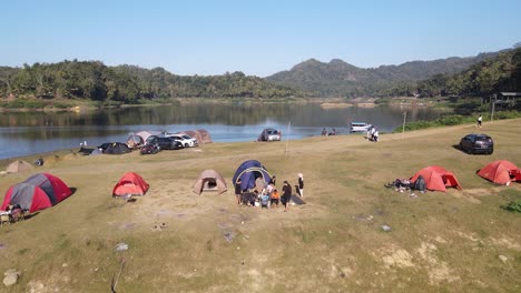 An-aerial-view-shows-several-people-camping-relaxing-and-cooking,-in-a-plain-area-near-the-Sermo-Reservoir,-Yogyakarta,-Indonesia