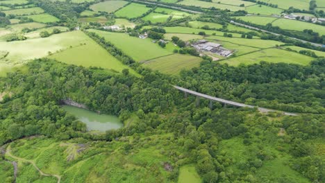 Toma-Aérea-Del-Viaducto-De-Meldon-Que-Muestra-La-Estructura-Histórica-En-Medio-De-Una-Exuberante-Vegetación-Y-Colinas-Onduladas