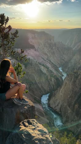 Vertical-View,-Young-Woman-on-Vista-Point-Above-Yellowstone-National-Park-Grand-Canyon-on-Golden-Hour-Sunlight