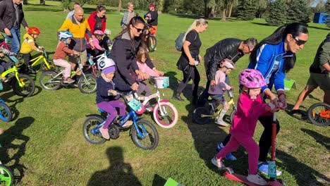 small-children-are-racing-with-bicycles-while-some-of-their-parents-are-helping-them