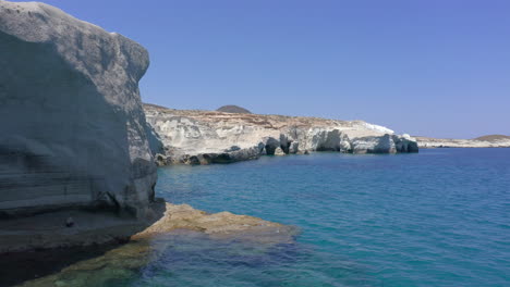 Aerial:-Low-flight-in-Sarakiniko-beach-o-Milos-with-white-rocks-coastline-and-caves