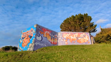 Looking-up-at-WW2-bunker-covered-in-graffiti-on-hill-at-The-Massey-Memorial,-Point-Halswell-in-Wellington,-New-Zealand-Aotearoa