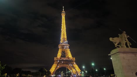 Artistic-evening-light-show-on-the-golden-illuminated-Eiffel-Tower-with-the-Olympic-Rings-symbol-before-the-2024-Games-in-Paris,-France