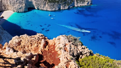 Top-shot-of-a-picturesque-view-of-the-blue-water-and-Zakynthos-Sala-of-Navagio-Pludmale-and-two-cameras-resting-on-the-foreground