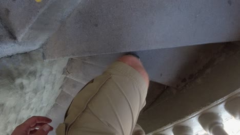 POV-looks-down-onto-man's-feet-climbing-concrete-staircase,-La-Piedra