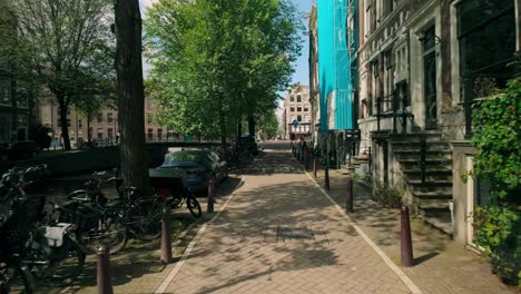 Amsterdam-canal-street-view-forward-with-houses,-car,-and-water-POV