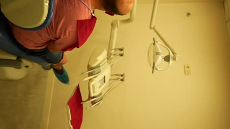 Panning-vertical-shot-of-a-patient-seated-in-a-dental-chair-looking-at-a-screen-in-a-dental-clinic