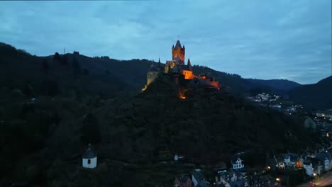 Vista-Aérea-Desde-Un-Dron-Del-Castillo-De-Cochem,-Renania-Palatinado,-Alemania,-En-Un-Hermoso-Cielo-Nocturno-Nublado