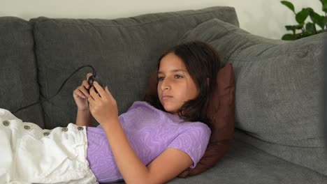 Bored-Hispanic-Kid-Girl-Playing-Retro-Video-Games-on-Sofa