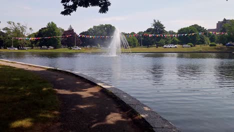 Traffic-at-Deering-Oaks-Park-showing-lake-and-fountain,-bridge-and-trees-at-Portland,-Maine