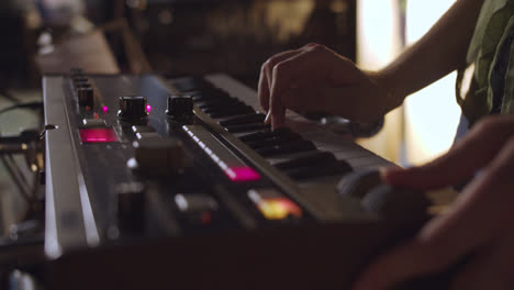 Beautiful-Close-up-shot-of-a-young-Caucasian-woman's-hands-playing-an-alternative-music-synthesizer-in-an-underground-rehearsal-room-with-lamps