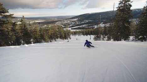 Male-skier-doing-big-carving-turns-on-a-slope-with-forest-all-around