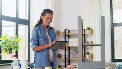 Möbelrestaurierung,-Heimwerken-Und-Heimwerkerkonzept.-Glückliche-Frau-Mit-Tablet-PC-Bereitet-Alten-Holztisch-Für-Die-Renovierung-Vor