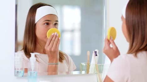 Schönheit,-Hygiene-Und-Menschen-Konzept-Teenager-Mädchen-Mit-Reinigungsschwamm-Reinigung-Gesichtshaut-Und-Blick-In-Den-Spiegel-Im-Badezimmer