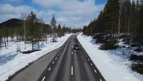 Car-Driving-On-Asphalt-Highway-Through-Snowy-Landscape-In-Sweden