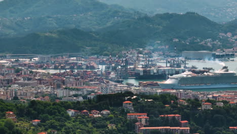 Puerto-De-La-Spezia-Con-Gran-Crucero,-Montañas-Y-Edificios-De-La-Ciudad-En-Italia,-Vista-Aérea