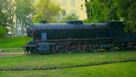 Wide-panorama-view-with-slow-right-pan-movement,-of-an-old-vintage-steam-locomotive-train,-exposed-at-Kalamata-railway-museum-,-Greece