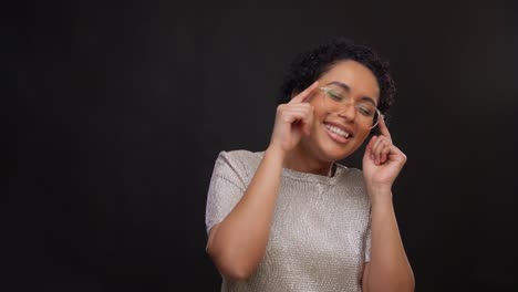 Concepto-De-Ocio-Y-Gente-Feliz-Mujer-Afroamericana-Con-Gafas-Bailando-Y-Dibujando-El-Corazón-En-El-Aire-Con-Los-Dedos-Sobre-Fondo-Negro