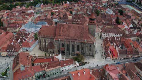 Schwarze-Kirche-In-Brasov,-Umgeben-Von-Historischen-Gebäuden-Mit-Roten-Dächern,-Luftaufnahme