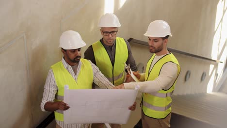 Male-Builder-in-Helmet-with-Blueprint-at-Window