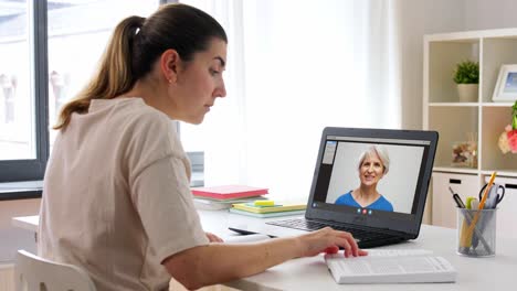 Educación,-Escuela-En-Línea-Y-Concepto-De-Aprendizaje-A-Distancia-Mujer-Estudiante-Con-Cuaderno-Y-Libro-Viendo-Videos-Tutoriales-En-Una-Computadora-Portátil-En-Casa