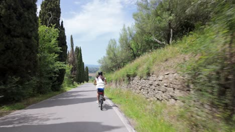 Frau-Auf-Elektrofahrrad-Fährt-Tagsüber-Durch-Die-Landschaft-Der-Toskana,-Italien