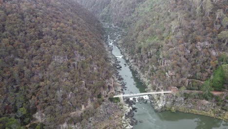 Vista-Aérea-En-4k-De-Un-Desfiladero-Con-Senderos,-Un-Puente-Colgante-Y-Una-Pequeña-Cascada-En-Un-Parque-Nacional-Australiano