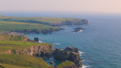 Herd-of-cows-graze-atop-coastal-cliffs-on-scenic-Porthcothan-coastline,-aerial