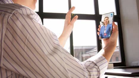 remote-job,-technology-and-people-concept--hand-of-woman-holding-smartphone-and-having-video-call-with-colleague-at-home-office