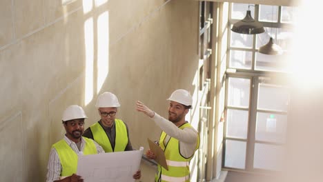 Männlicher-Baumeister-Im-Helm-Mit-Blaupause-Am-Fenster