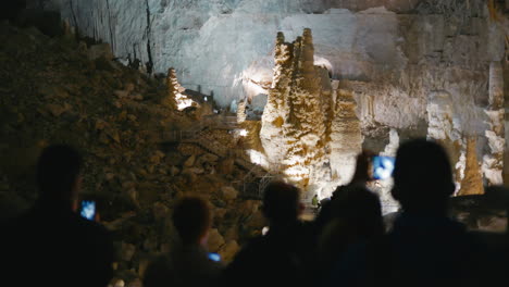 Frasassi-Caves,-group-of-tourist-visitors-inside-the-caves-during-the-guided-tour-underground-to-admire-the-geological-formations