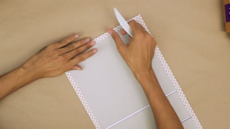 Person-carefully-crafting-a-hand-bound-book-with-precise-tools-and-materials,-close-up,-indoors