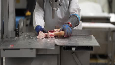 Cow-leg-bone-being-sliced-in-medallions-by-a-linear-saw-at-a-meat-processing-plant,-Close-up-shot