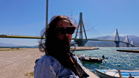 Beautiful-woman-admires-majestic-bridge-of-Charilaos-Trikoupis-Rio-in-Greece-on-windy-day