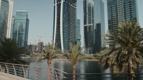 Genießen-Sie-Einen-Weiten-Blick-Auf-Die-Jumeirah-Lake-Towers-Mit-Ihrer-Ruhigen-Umgebung-Aus-Wasser-Und-Palmen,-Die-Die-Beeindruckenden-Gebäude-Hervorheben