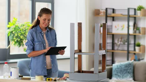 Möbelrestaurierung,-Heimwerken-Und-Heimwerkerkonzept.-Glückliche-Frau-Mit-Tablet-PC-Bereitet-Alten-Holztisch-Für-Die-Renovierung-Vor