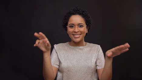 Concepto-De-Ocio-Y-Gente-Feliz-Mujer-Afroamericana-Con-Gafas-Bailando-Y-Dibujando-El-Corazón-En-El-Aire-Con-Los-Dedos-Sobre-Fondo-Negro