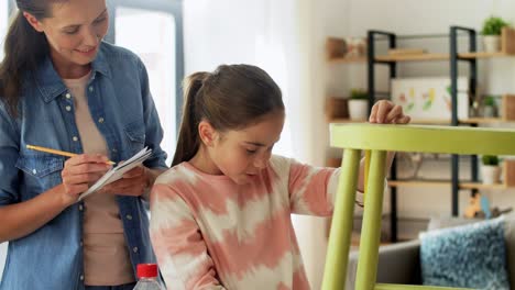 Madre-E-Hija-Con-Regla-Midiendo-Una-Silla-Vieja