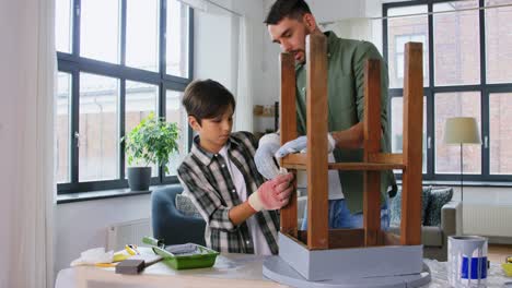 renovation,-diy-and-blogging-concept--father-and-son-in-gloves-sticking-adhesive-tape-to-old-wooden-table-for-repainting-and-recording-tutorial-video-at-home