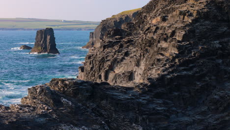 Rugged-and-weathered-sea-cliffs-and-coves-along-Cornwall-coast,-aerial-trucking