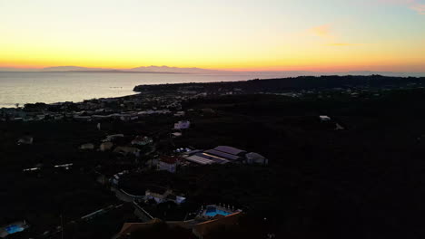 Greek-coastal-town-after-sunset,-aerial-orbit-view