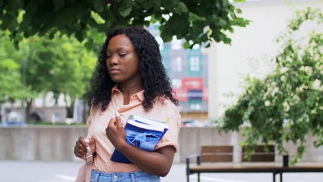 education,-school-and-people-concept--happy-smiling-african-american-student-girl-with-notebooks-in-city